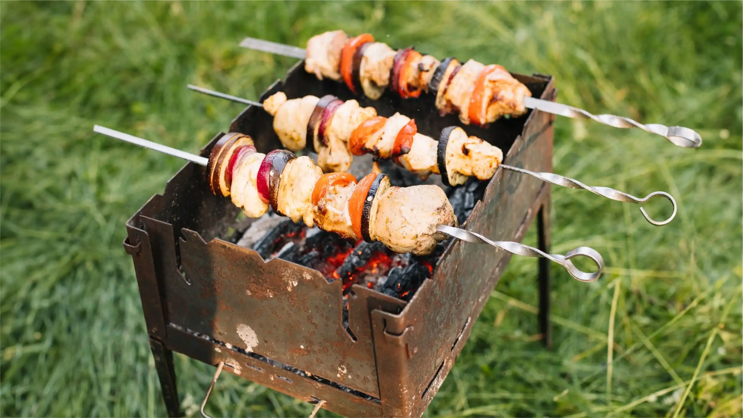 mini parrilla en mal estado, con óxido cocinando unos pinchos